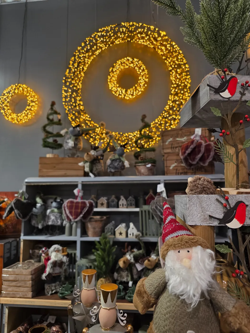 Winterliche Figuren unter beleuchteten Kränzen